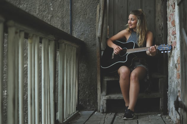 Woman Wearing Gray Tank Top Playing Black Cutaway Acoustic Guitar
