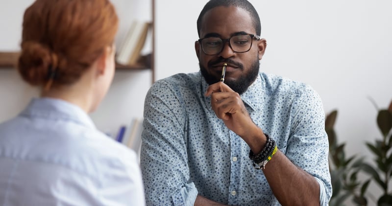 a man considering a question with a pen to his mouth
