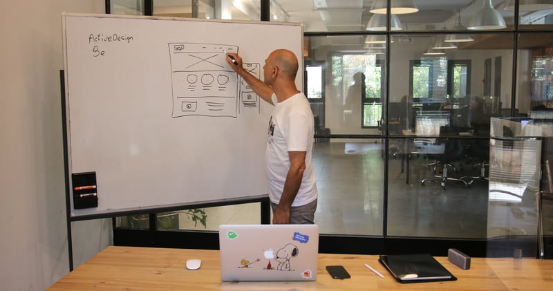 Concentrated male entrepreneur analyzing project standing near whiteboard in modern workspace