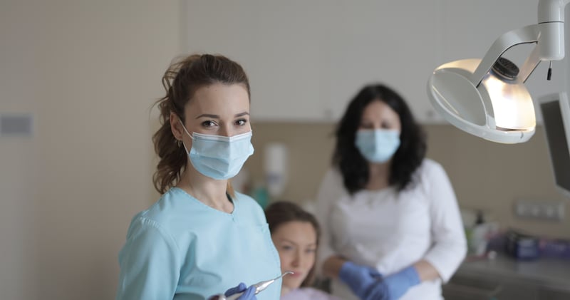Female dentists treating teeth of patient in modern clinic