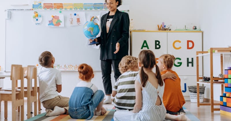Teacher holding globe in front of class