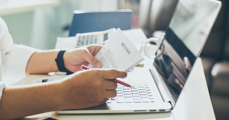 Person holding resume with red pencil