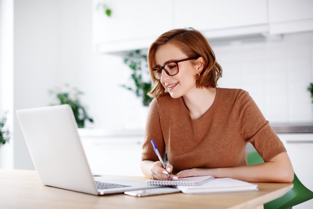 Young woman taking notes in front of a laptop