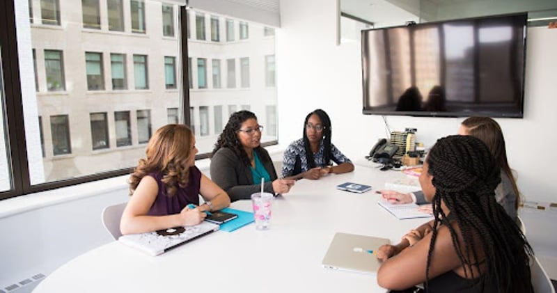 5 women talking at meeting table