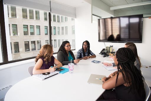 5 women talking at meeting table