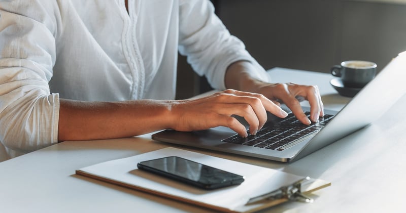 Woman reviewing resumes on laptop at desk