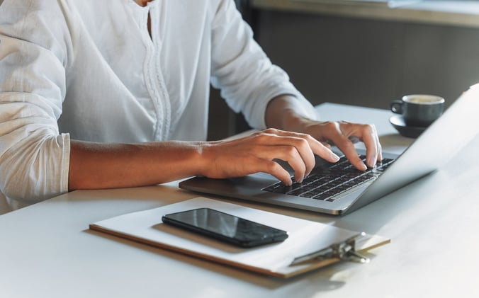 Woman reviewing resumes on laptop at desk